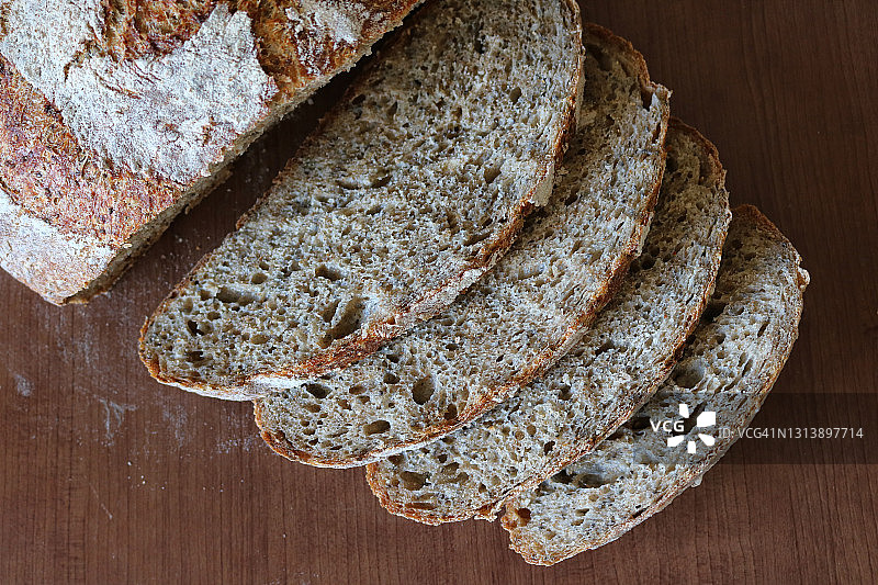 面对你的面包!荷兰烤箱不揉全麦面包。切片图片素材