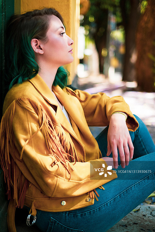 墨西哥城，一位绿色头发的年轻女子坐在镜头前图片素材