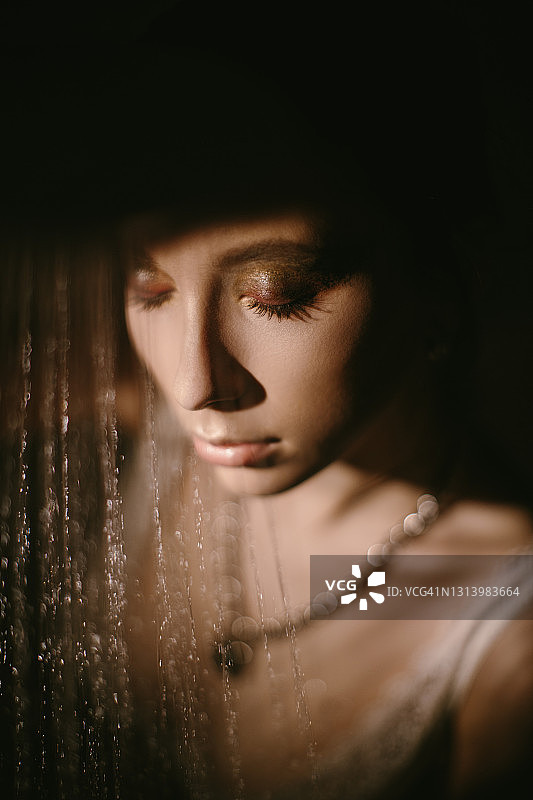 年轻的黑发女人的肖像在低调的内衣通过水从淋浴滴。模特向下看。图片素材