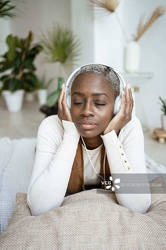 一个躺在家里闭着眼睛听音乐的漂亮女人图片素材