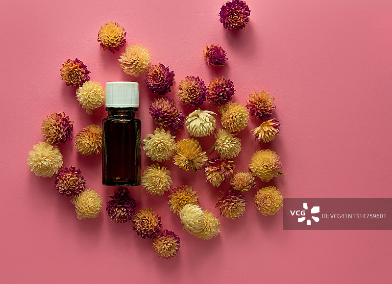草本精油玻璃瓶模型粉色花朵背景。替代医学皮肤护理水疗芳香疗法图片素材