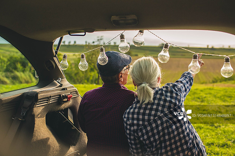 一对快乐的老夫妇坐在他们的汽车后备箱里图片素材