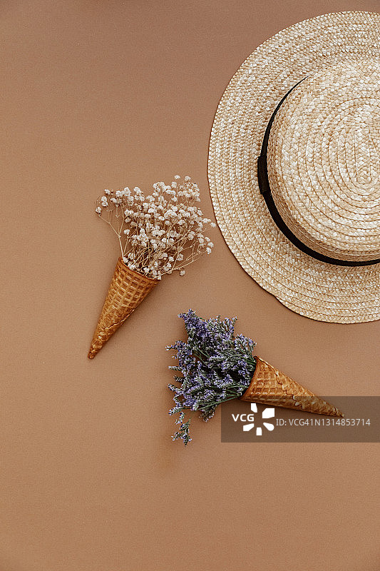 创意的夏季背景与华夫蛋筒，草帽和鲜花在棕色的背景图片素材