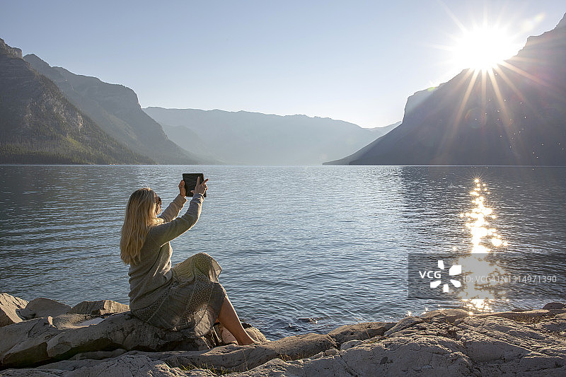 女人在山湖边休息，拍照图片素材