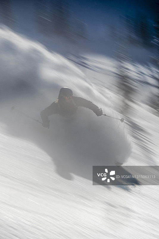 滑雪者下着厚厚的粉状雪穿过森林图片素材