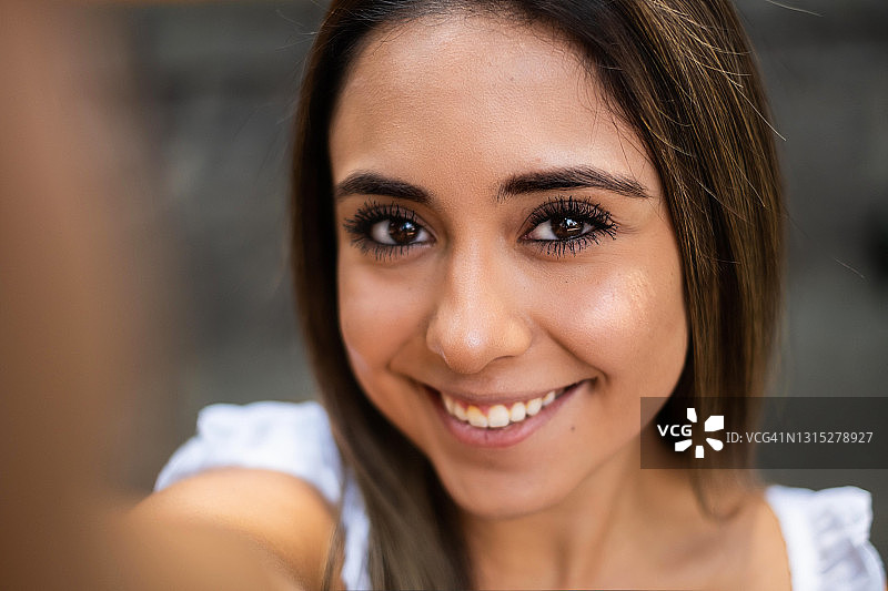 在墨西哥城，一名年轻的西班牙女子微笑着自拍，用手机拍摄图片素材