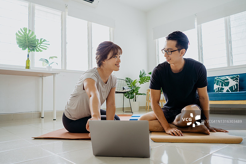 年轻的亚洲夫妇用笔记本电脑上在线瑜伽课图片素材