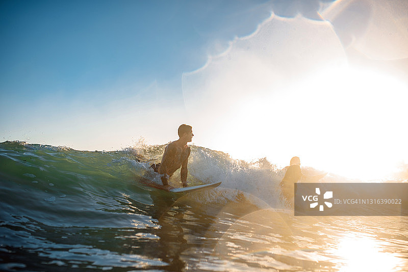 黄金海岸冲浪者在日出时赶上海浪图片素材