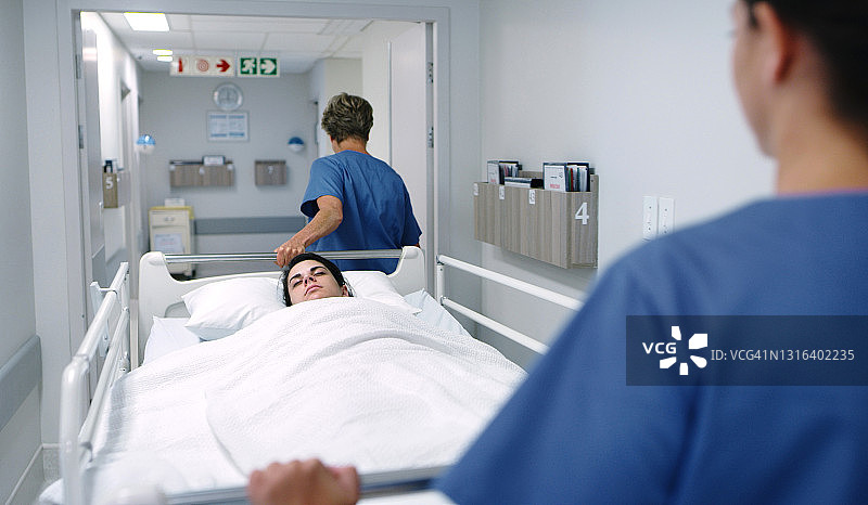 一名女病人被两名女护士推着躺在病床上图片素材