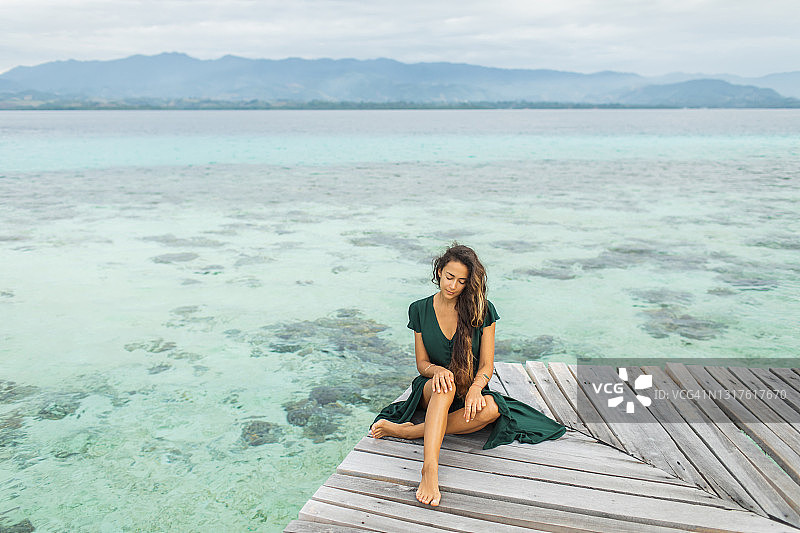 迷人的夏季肖像年轻女子坐在木制码头的热带岛屿图片素材