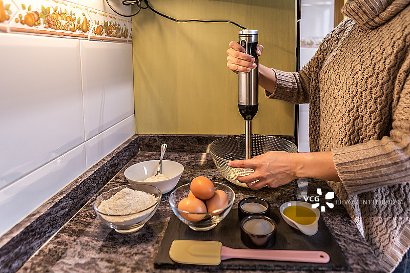 在厨房里用搅拌机准备糕点的女人图片素材