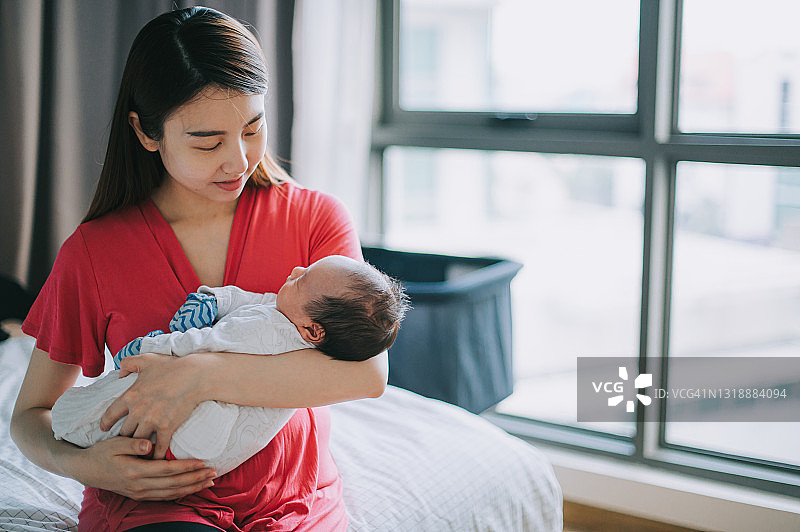 肖像亚洲华人母亲抱着她的儿子婴儿在卧室里图片素材