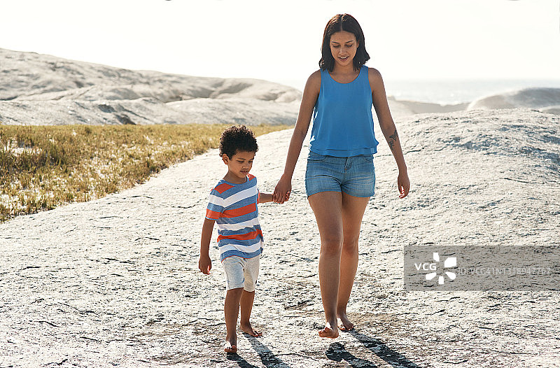 一位母亲和她的儿子在海滩上散步图片素材