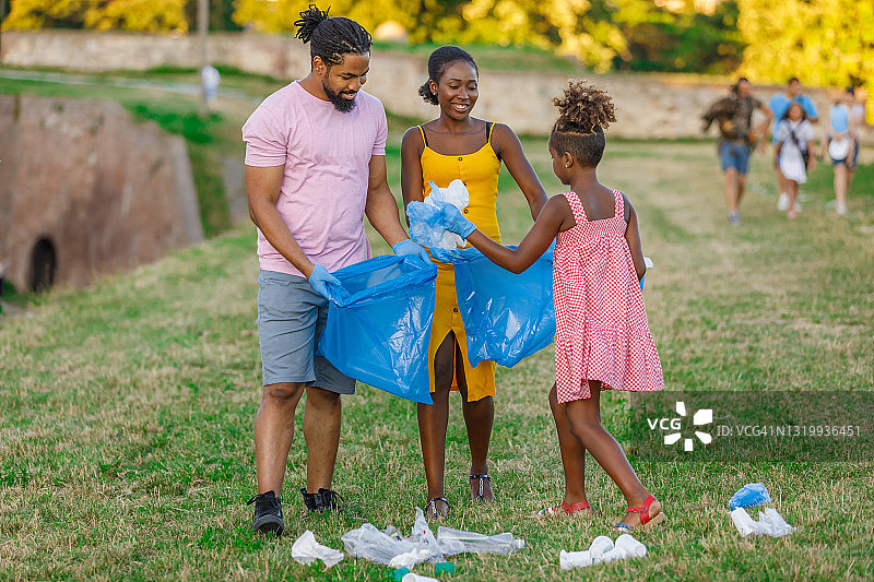 快乐的非裔美国家庭正在收集垃圾袋里的垃圾。图片素材