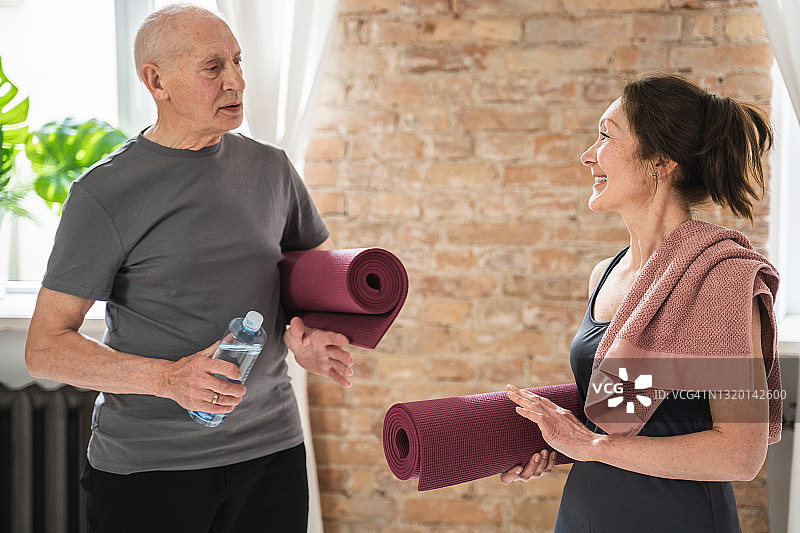 两位活泼愉快的老人拿着运动垫准备锻炼图片素材