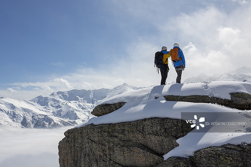 登山队员们停在白雪覆盖的山顶向外张望图片素材