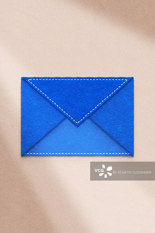 蓝色的信封，用毛毡制成，阴影很长图片素材