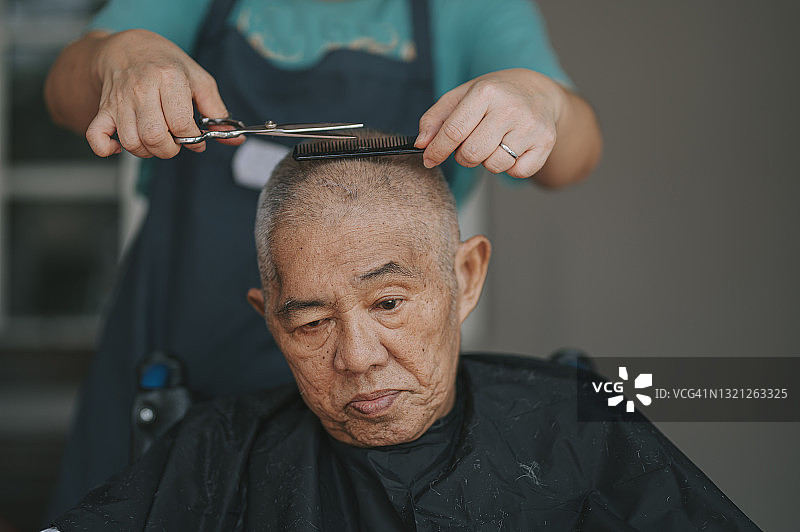 坐在轮椅上的华裔老人在自家前院理发图片素材