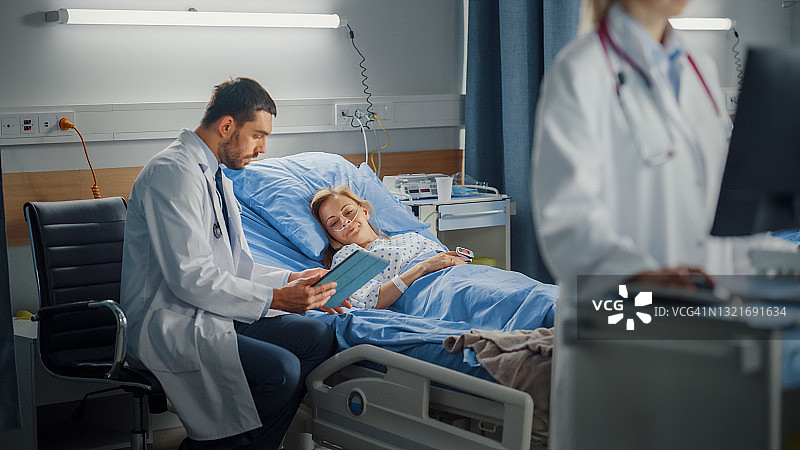 医院病房:专业女医生使用医用电脑。在现代设备的背景下，临床外科医生使用平板电脑在床上咨询手术成功后恢复的患者图片素材