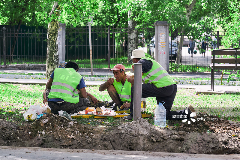 在俄罗斯佩尔姆，一队外来工人在休息期间在街上吃午饭图片素材