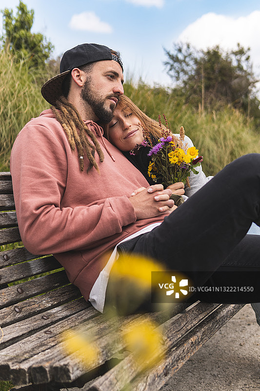 一名年轻女子在长凳上靠在男友的肩膀上放松图片素材