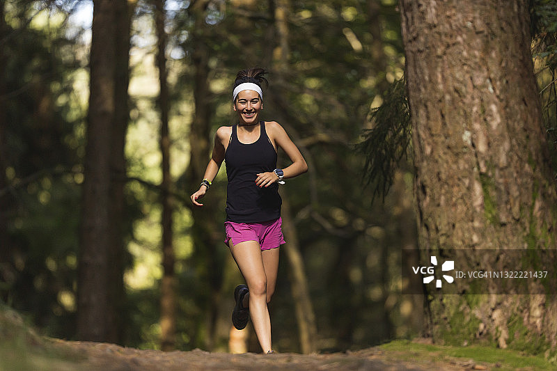 快乐的女人在森林里奔跑图片素材