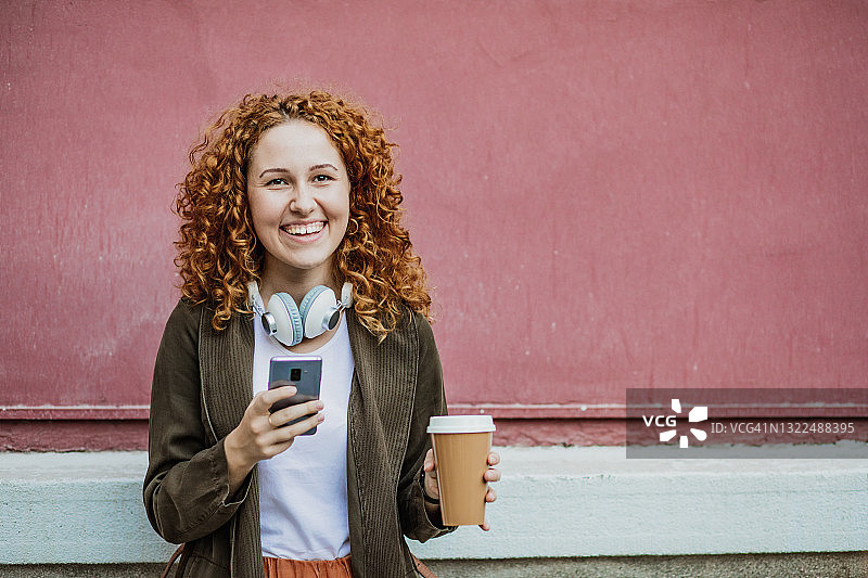 一个年轻女子使用手机和洞可重复使用的咖啡杯的肖像图片素材