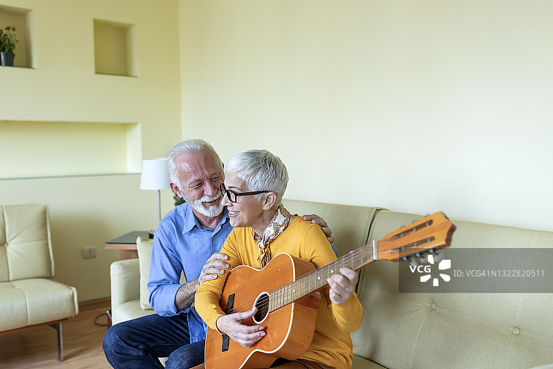 一位老年妇女很乐意弹吉他，向她的丈夫表达爱意。图片素材