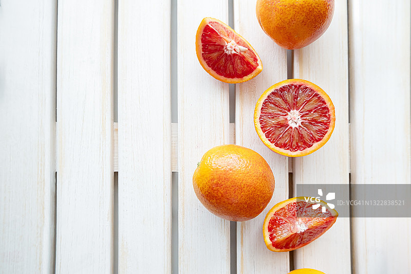 木制背景上的成熟的红橙子。切片成熟多汁西西里血橙在白色的木制背景。副本的空间。图片素材