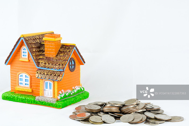 房子模型在一堆孤立的白色背景上的硬币图片素材