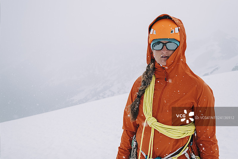一名女登山者在暴风雪中攀登冰川上复杂的地形图片素材