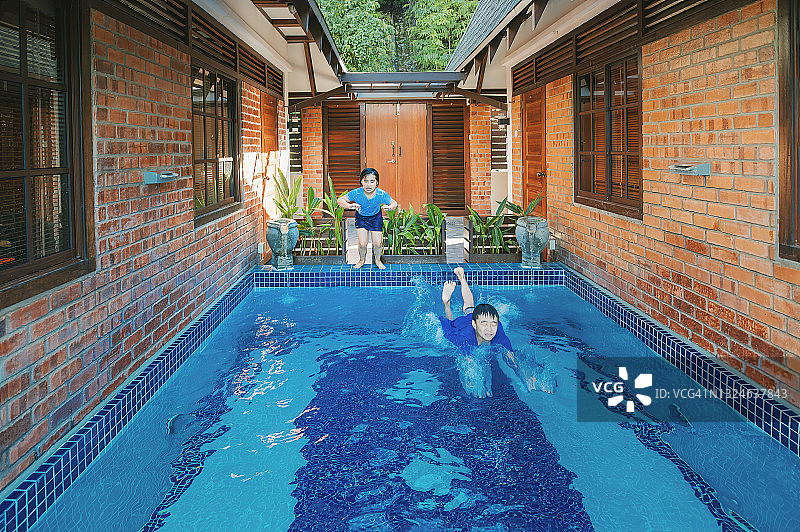 亚洲华人年轻的兄弟姐妹喜欢在周末在家游泳图片素材