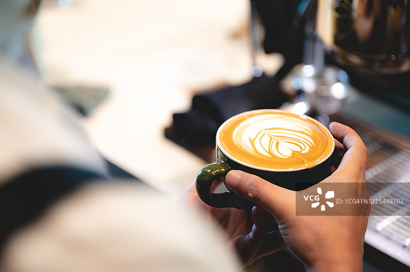 专业的咖啡师将浓缩咖啡制作成咖啡杯，在咖啡厅，咖啡机中饮料，人用手倒热水，在早上的业务早餐，新鲜的香气在热饮图片素材