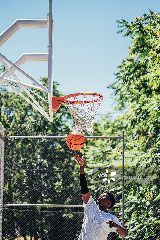 一个黑人非洲男孩跳进篮筐投篮的肖像。在城市的球场上打篮球。图片素材