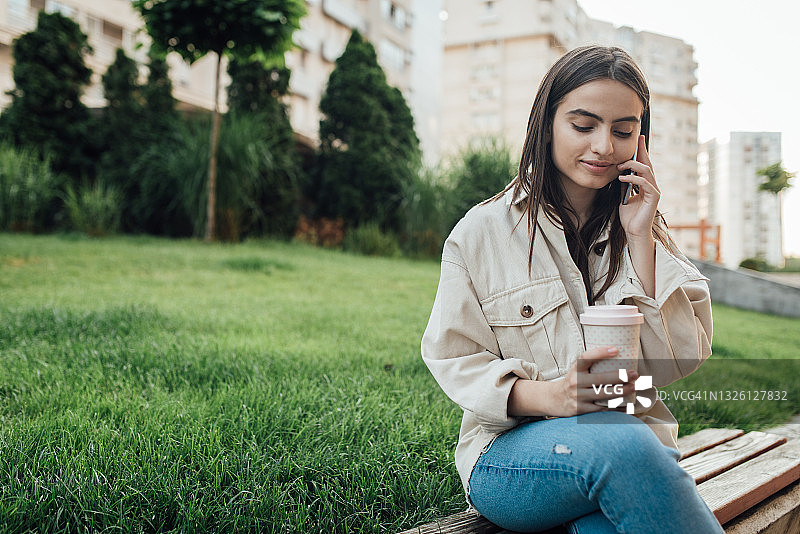 一个女孩在喝咖啡休息时间用手机聊天图片素材
