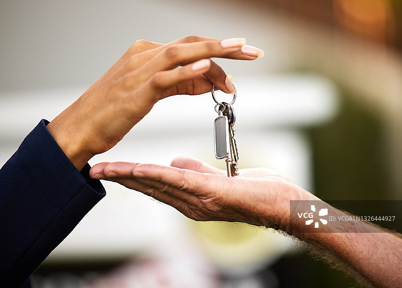 一名面目全非的女性房地产经纪人在外面把新买房子的钥匙交给了她的男性客户图片素材