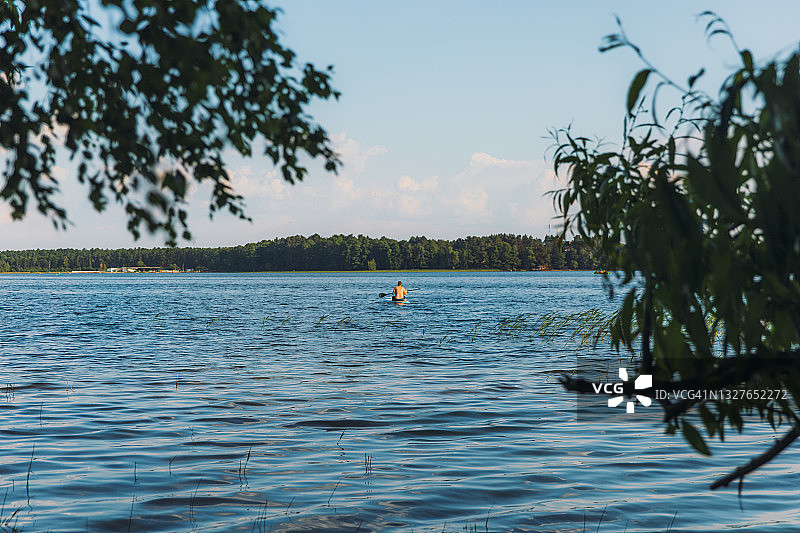 夏日，人们在湖边玩桨板，欣赏森林美景图片素材