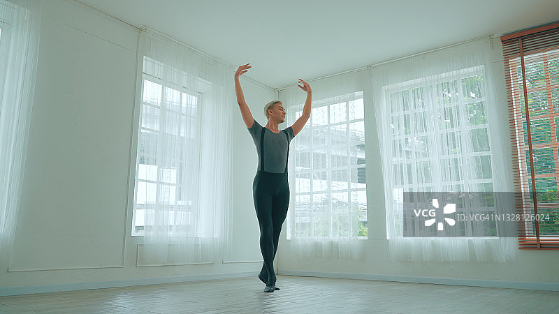 一名男芭蕾舞者在一扇大窗户前跳舞，工作室背景是年轻时尚的现代芭蕾舞者图片素材