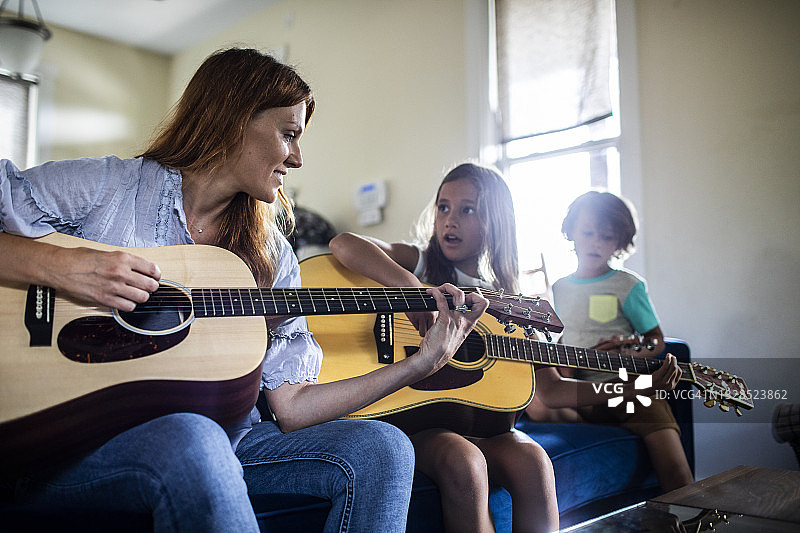 母亲和女儿在弹吉他，儿子在用梳子唱歌图片素材