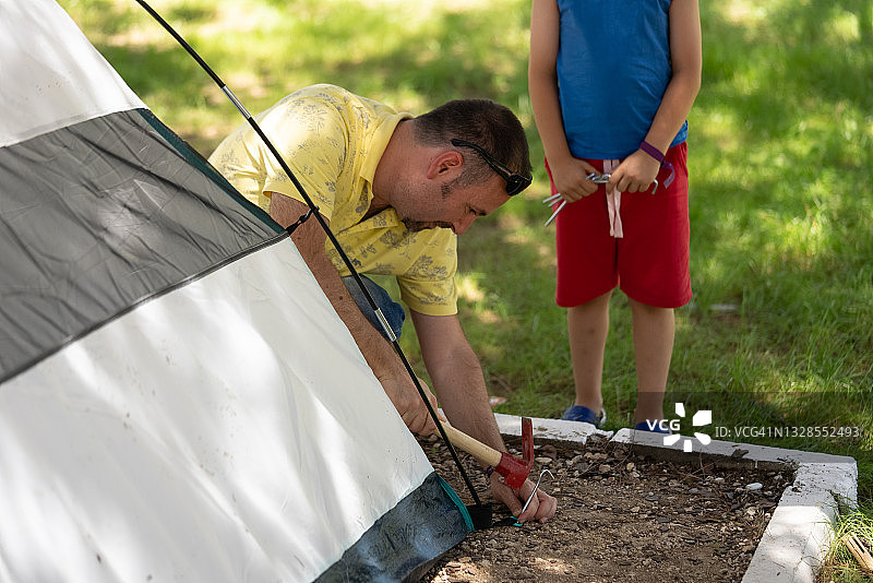 父亲和儿子在往地里钉帐篷的钉子图片素材
