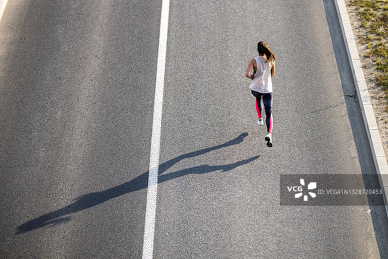 一个年轻女子在路上慢跑图片素材