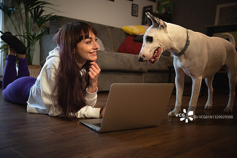 一个女人和她的狗在家里使用笔记本电脑图片素材