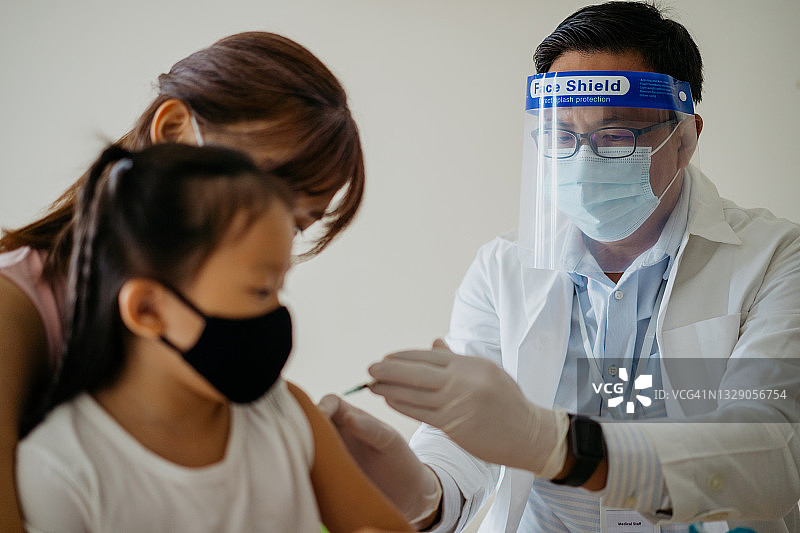 医生正在给一个小女孩的手臂注射疫苗图片素材