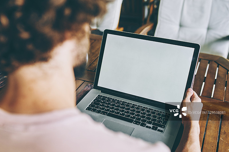 一个年轻人正在一家咖啡馆里用一台白屏笔记本电脑工作图片素材