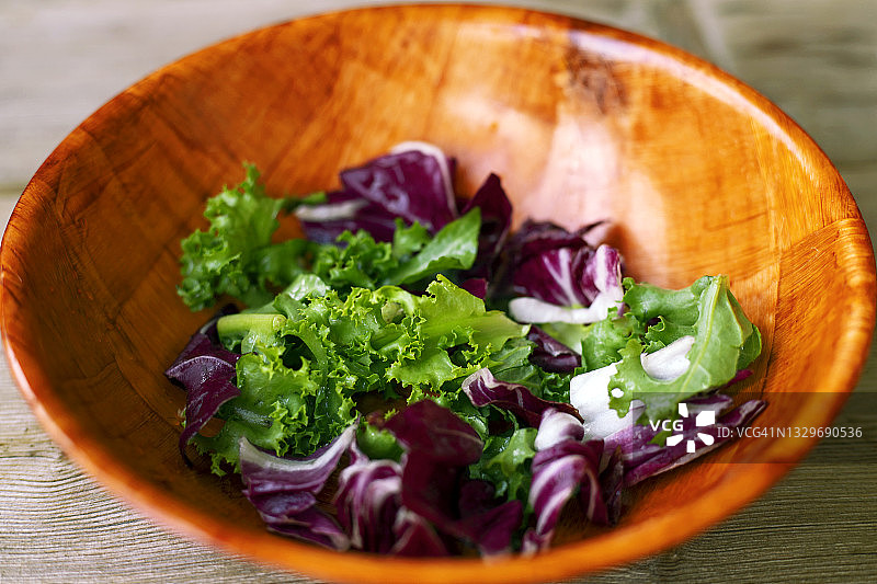 绿叶沙拉，紫色竹碗放在木桌的背景上。健康饮食与节食概念图片素材