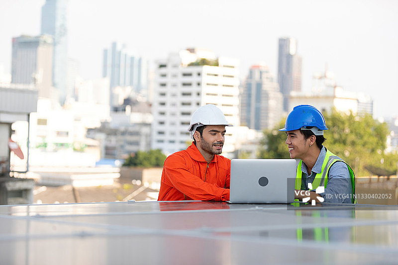 工程师或技术人员一边用笔记本电脑讨论项目，一边检查屋顶上的太阳能电池板图片素材