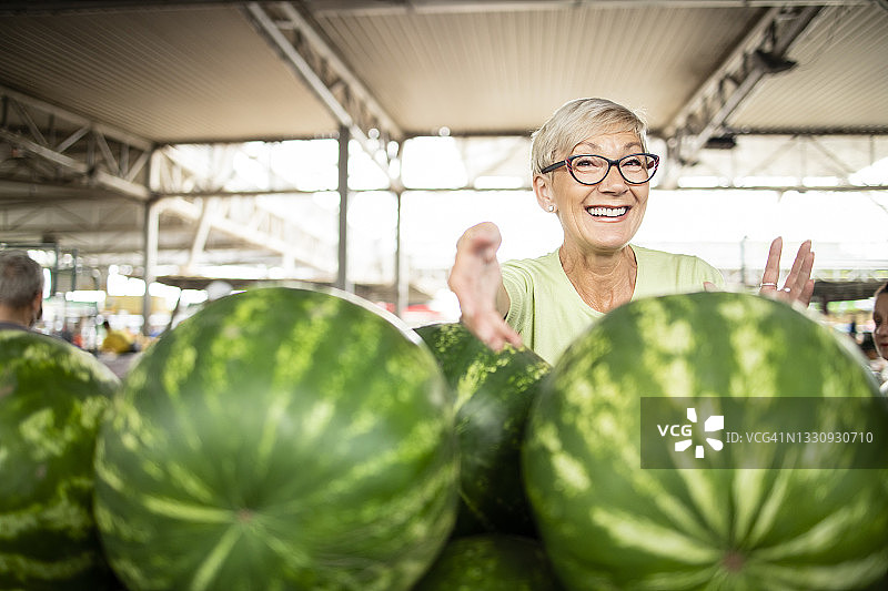 妇女肖像在市场出售新鲜的有机西瓜。图片素材