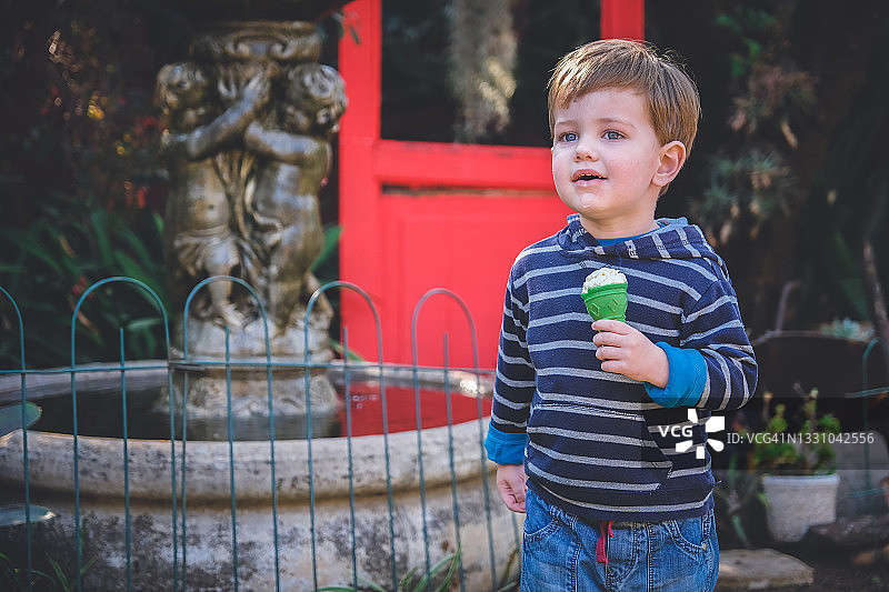 可爱的男孩拿着绿色的冰淇淋蛋卷图片素材