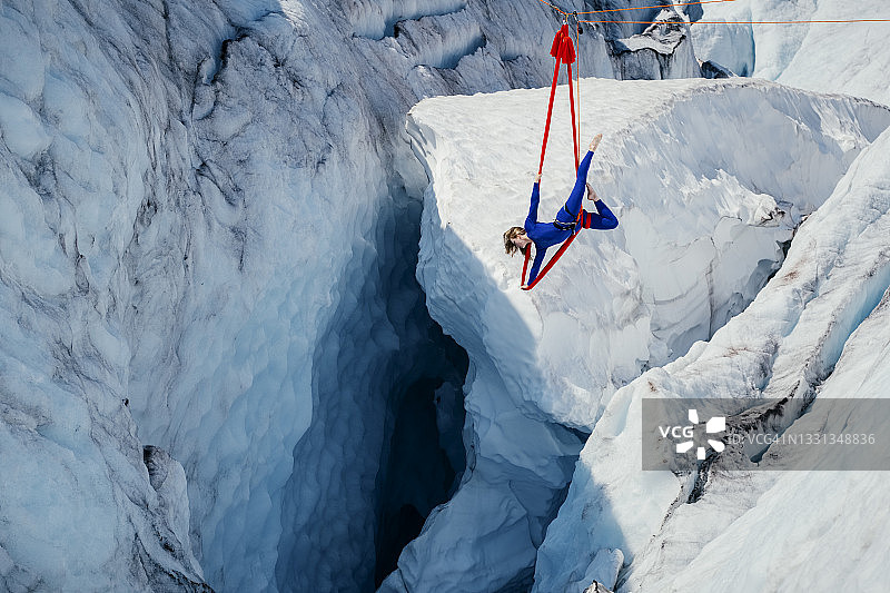 一名女子在冰川裂缝深处的空中吊床上表演动态特技图片素材