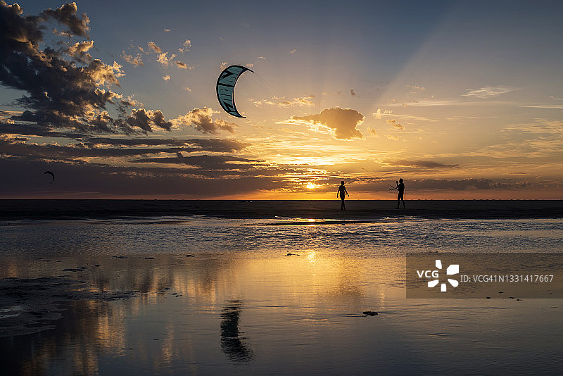 两个风筝冲浪者的剪影在日落，洛斯兰斯海滩，塔里法，加的斯省，安达卢西亚，西班牙图片素材